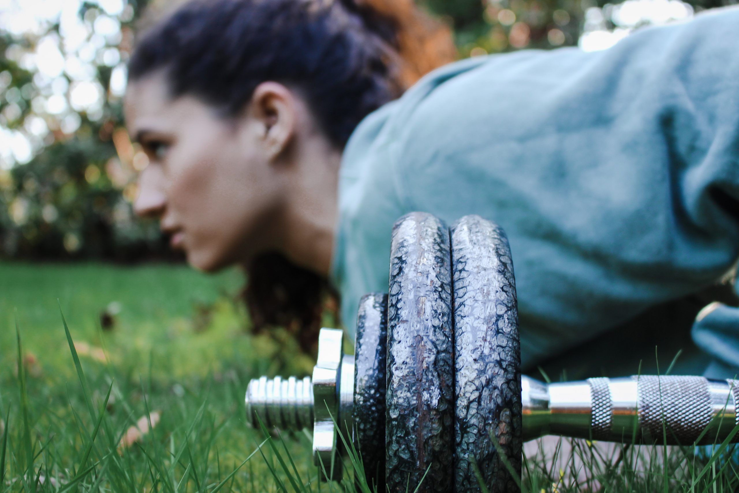 Woman in a personal training session lifting barbell above her head. 